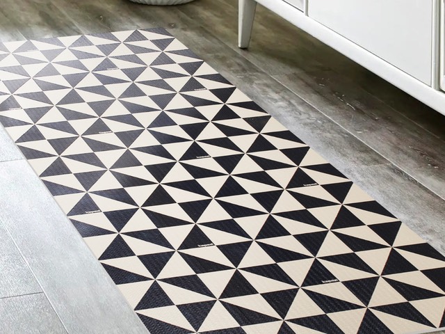 Passadeira Flex com estampa de triângulos em preto e branco, em um corredor com piso de madeira