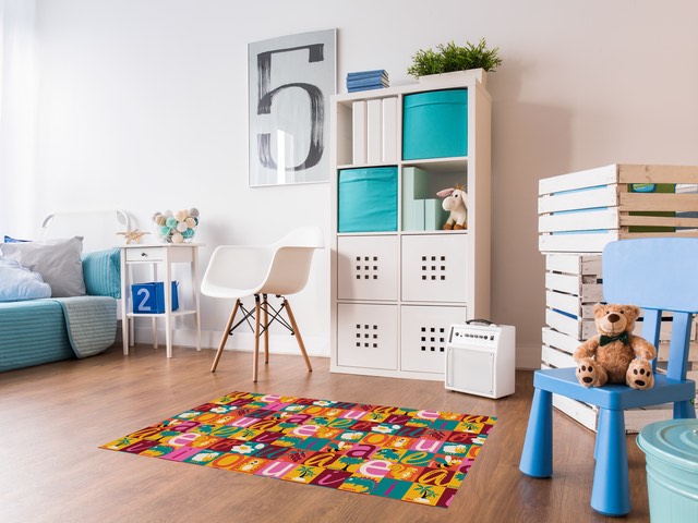Quarto infantil decorado com o tapete de estampa de vogais colorida no centro do piso de madeira